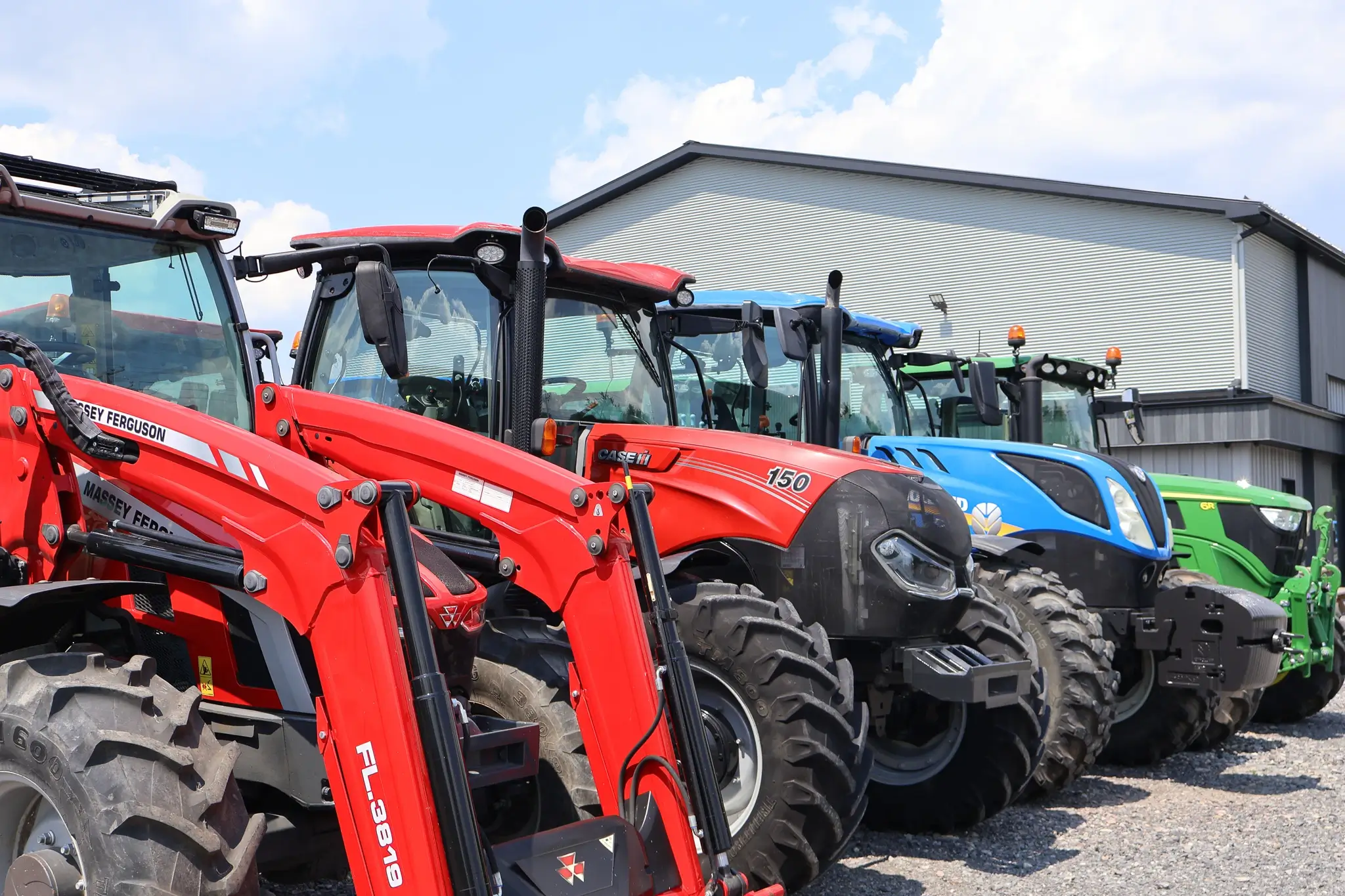 Agricultural tractors lined up for sale outside a farm equipment dealership.